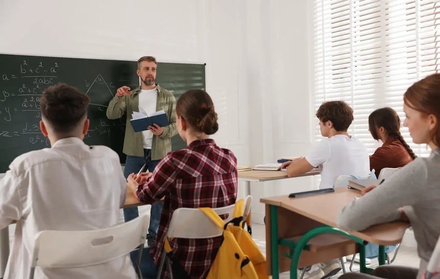 manual student account management creates security risks and disrupts classroom function with teacher standing in front of students sitting at desks