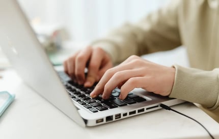 student sitting at a desk typing on a laptop