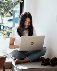 female student logging into her lap top at home